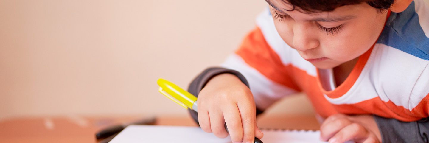 Se ve a un niño con un lápiz y un cuaderno