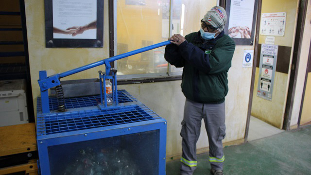 Imagen de una compactadora de botellas y un trabajador